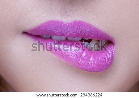 Closeup of sensuous woman biting pink lips