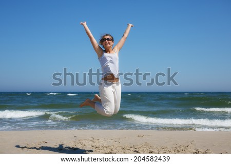 Woman in a jump shot on the beach of the Baltic sea in summer