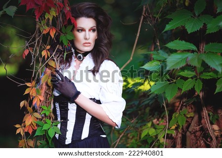 Mysterious woman in Victorian dress among the autumn leaves