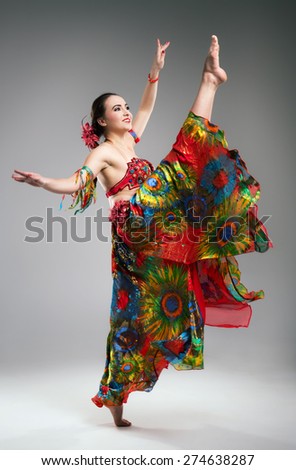 Beautiful young woman in colorful dress dancing in the studio