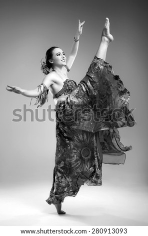 Beautiful young woman in a dress dancing in the studio