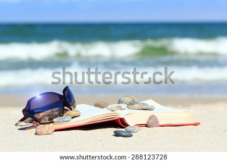 Book and sun glasses on the beach