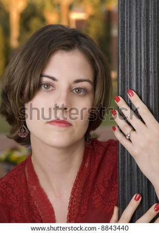 Outdoor head shot of an attractive 30 year old female model with hand on a lamp post.