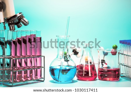 microscope and laboratory test tube on light blue background , science research equipment concept