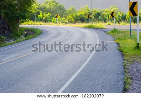 An empty S-Curved road with sign