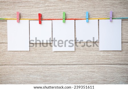 empty white photo frames hanging with clothespins on wooden background