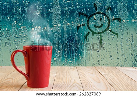 red coffee cup with smoke and sun sign on water drops glass window background