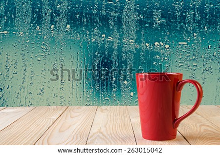 red coffee cup with natural water drops on glass window background