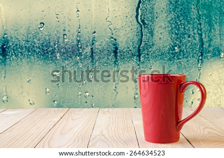 red coffee cup with natural water drops on glass window background