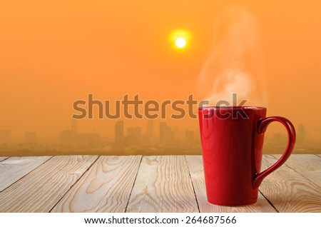 red coffee cup with smoke on sun rise background