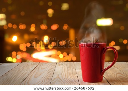 red coffee cup with smoke on city bokeh background