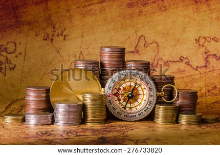 Compass and stack of coins on old map