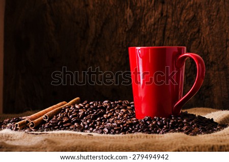 Red Coffee cup and coffee beans around on wooden table