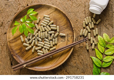 Pills in wooden dish and spilling from Bottle