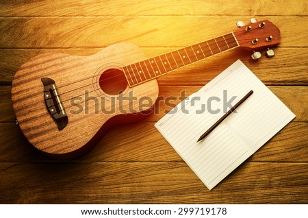 ukulele guitar with blank notebook and pencil