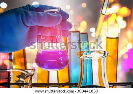 Double exposure of scientist hand holding laboratory flask.