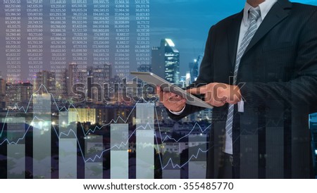 business man using tablet monitor graph on screen with night city background