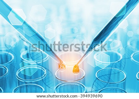 science pipette with a drop of substance over laboratory test tubes
