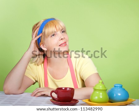 Mature housewife dreaming and drinking tea or coffee in the kitchen