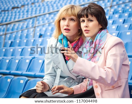 two excited  women fans watching  competition or concert in stadium