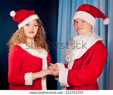Happy mature couple in love wearing Santa hats near Christmas tree. Fat woman and slim  fit  man.