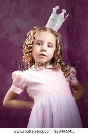 Arrogant little princess posing over dark pink background