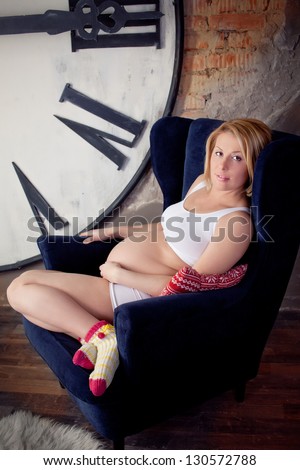 Pregnant blonde woman  near huge clock-face, big watch