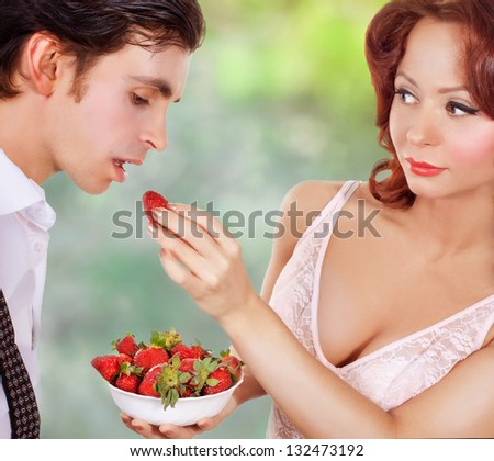 Sexy young couple. Woman feeding man strawberries