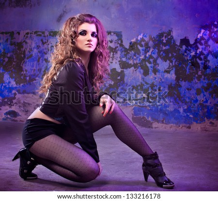 Young curly model posing against scrapped wall, smoky eyes, beautiful hair
