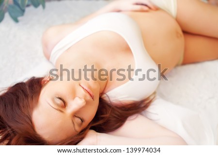 Pregnant blonde woman relaxing on sofa, sleeping, dreaming,