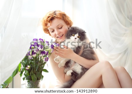 Portrait of a beautiful red haired curly female model  with grey cat