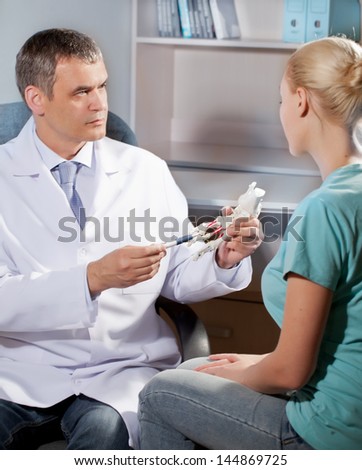 Orthopedic doctor in his office with the model of the feet and patient