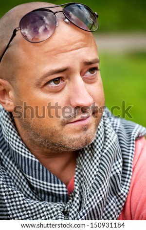 handsome bold man wearing 	neck handkerchief resting outdoor