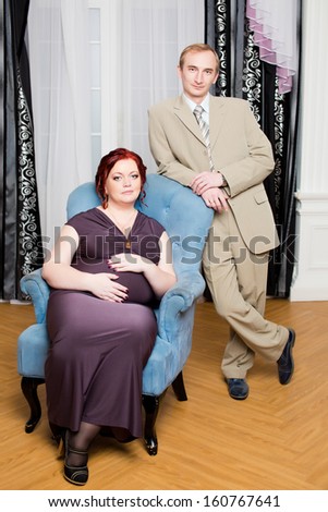 Pregnant couple posing at home, plus size overweight woman and slim man