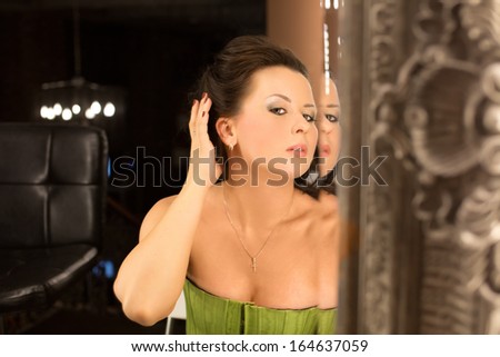 A girl sitting in front of a mirror. A young girl sitting in front of a big mirror and looking away of her reflection, mirror stage concept shot