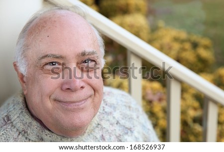 bold elderly man relaxing on the porch wearing knitting sweater