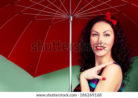Brunette pin up model posing wearing striped dress posing with red umbrella
