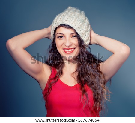 prettu long hair brunette girl wearing red shirt playing with warm knit hat