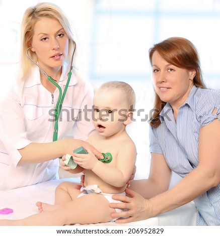 Portrait of a cute baby held by mother and being examined my doctor using stethoscope