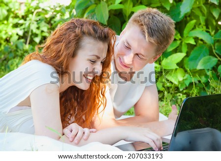 YOung couple with computer in the park having fun