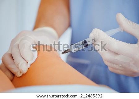 DOctor making injection in knee in his office