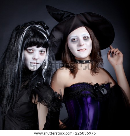 Teen girls wearing as witches for Halloween over dark background