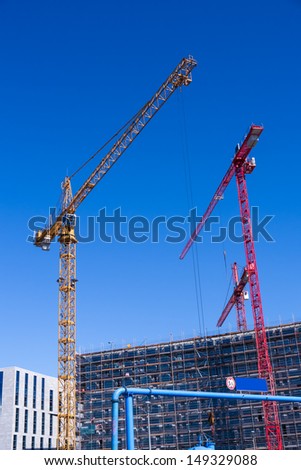 construction site with orange and red cranes and blue summer sky