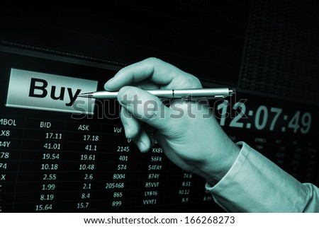 trading on stock market, pointing with pen on buy button