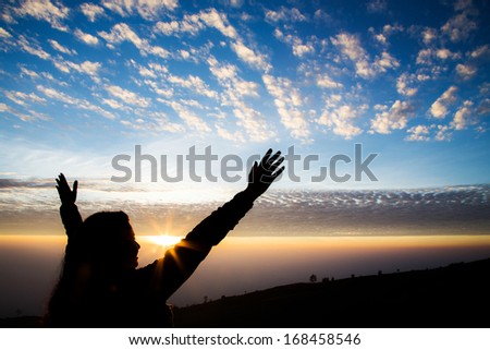 Girl silhouette with open arms freedom feeling over sunrise background