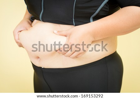 Woman\'s fingers measuring her belly fat