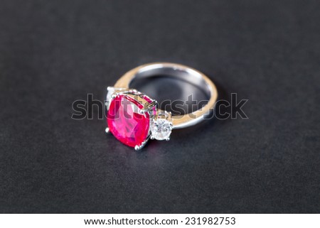 Closeup of diamond ring with ruby gem on black background