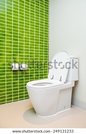Clean, white  toilet and paper rolls with Lime green mosaic tiles wall in bathroom