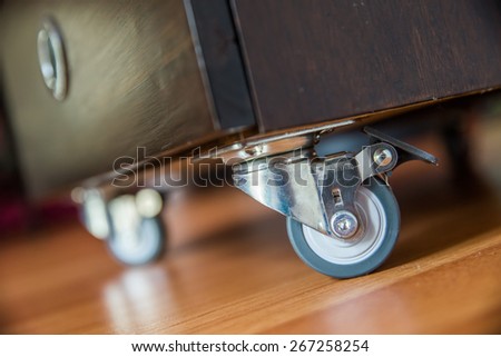 Standing small metal furniture wheel on wooden  floor