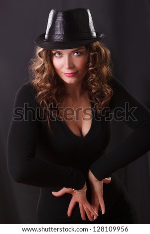 Glamor Portrait  of beautiful young woman in black hat and brown long ringlets hair posing